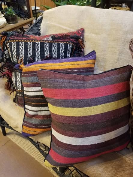 Striped kilim pillows in burgundy, mustard, and cream stacked on a linen sofa